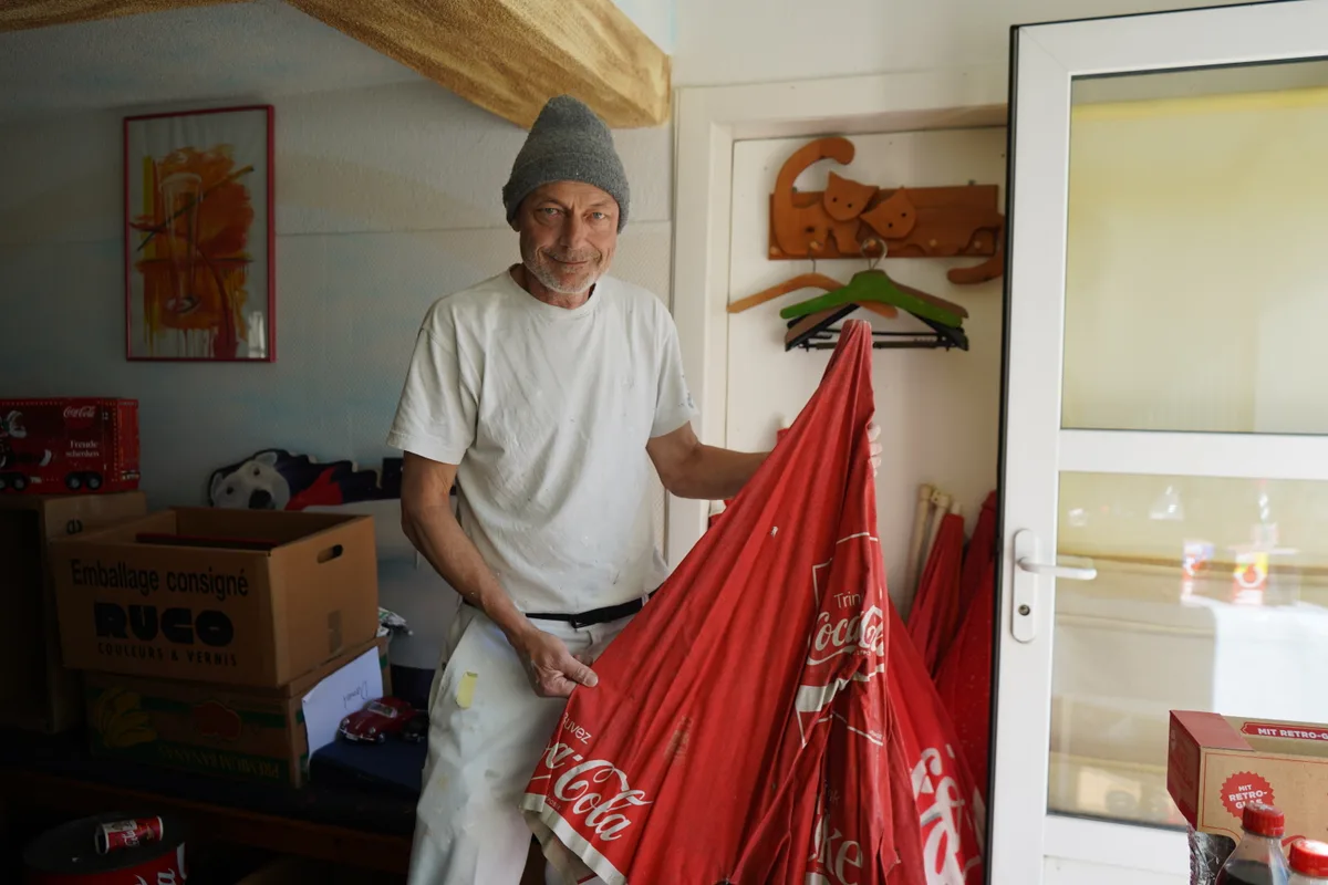 Man sieht Daniel Jaussi und seine Coca-Cola Sammlung.